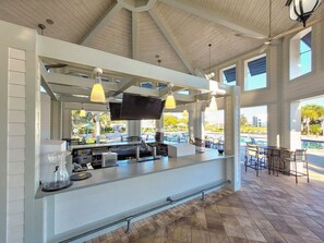 A bar area with a counter, bar stools, a television, and a ceiling fan. - Last Minute Disney! Private Pool, Game Room & Themed Bedrooms. Book Now! #56087 (Orlando)