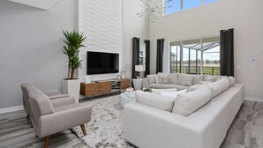 Ein modernes Wohnzimmer mit Flachbildfernseher, einer großen Couch, einem Couchtisch und einer Topfpflanze.