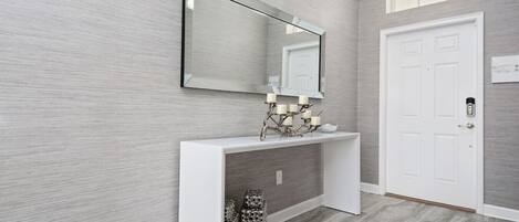 A hallway with a white console table, a mirror, and a door.