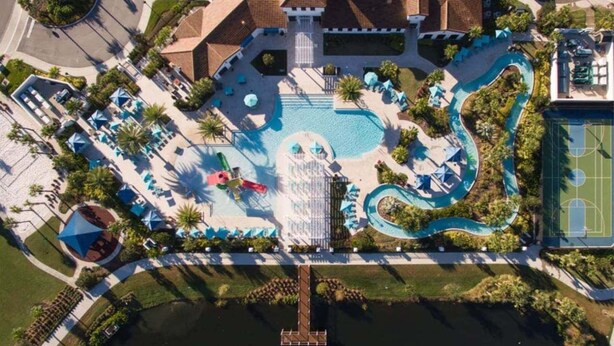An aerial view of a resort with a central pool, a tennis court, and a dock extending into a body of water. - Last Minute Disney Getaway! Private Pool & Themed Bedrooms. Book Now! #56089 (Orlando)