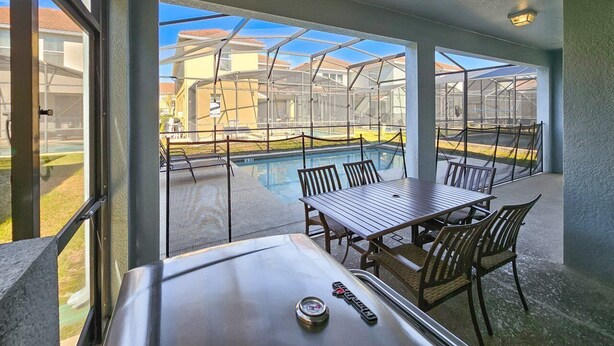 Ein Balkon mit Pool, Sitzgelegenheit im Freien und Blick auf umliegende Häuser.
