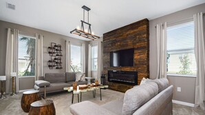 Ein modernes Wohnzimmer mit Kamin, Flachbildfernseher und einer gemütlichen Sitzecke.