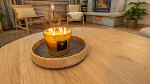 A round wooden table with a candle in a glass holder. - Hotel Sarazena (Zermatt)