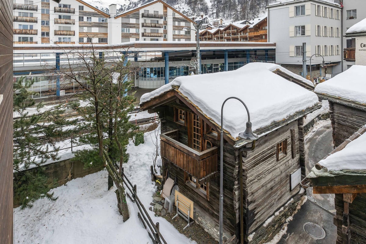 A snowy mountain town with wooden buildings and a modern hotel in the background.