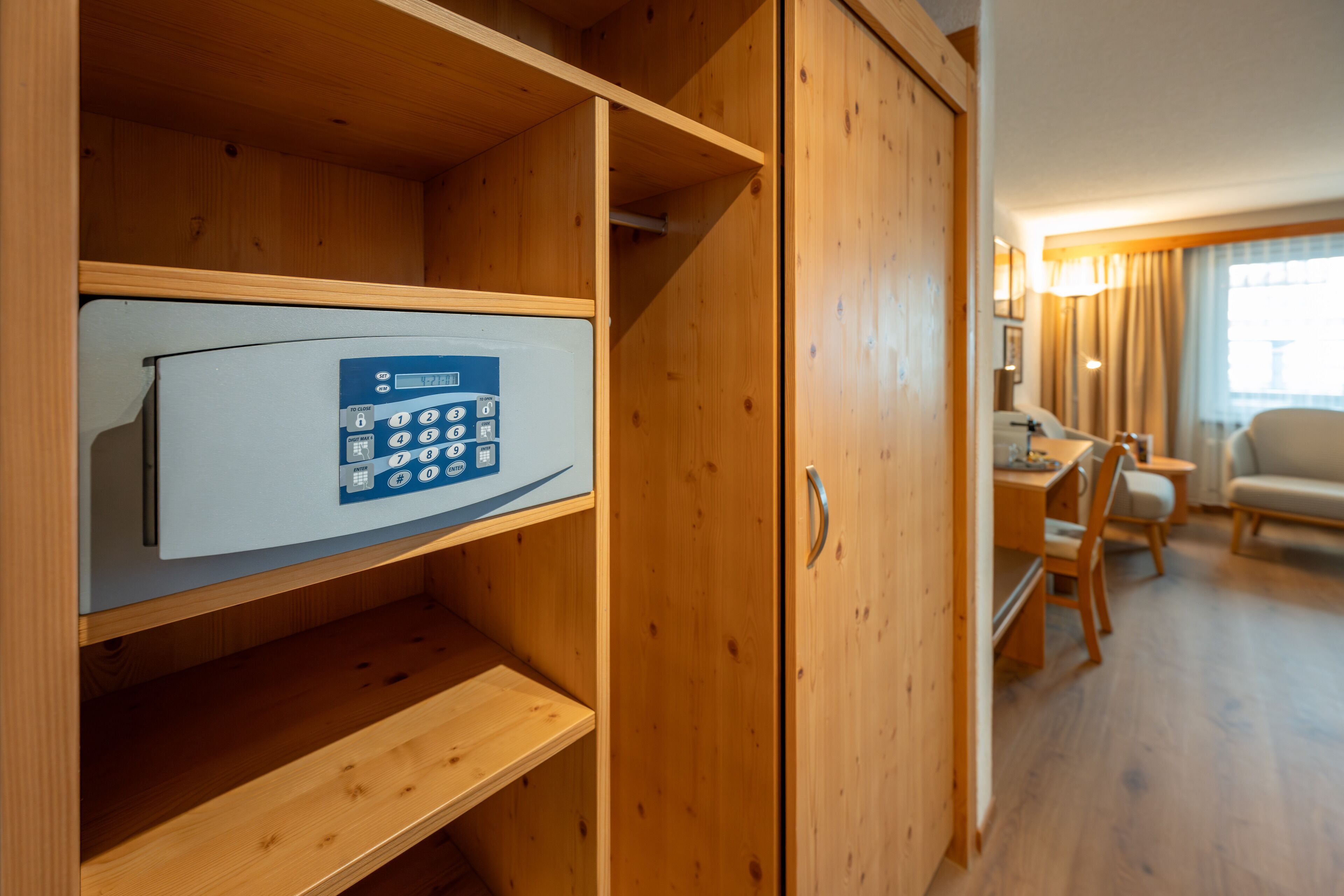 Habitación de hotel con armario de madera, minibar, escritorio y una silla.