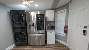 A compact kitchen with a stainless steel refrigerator, microwave, and built-in oven.