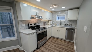 A modern kitchen with white cabinets, a stainless steel stove, and a dishwasher.
