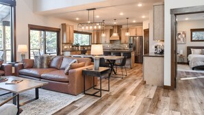 A spacious living area with a leather sofa, a dining table, and a kitchen with modern appliances. - Incredible New 3200+ Sq. Ft. Lodge w/ Arcades, Shuffleboard, Hot Tub, Paved! (Lead)
