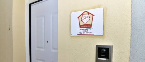 A door with a sign indicating "A San Lazaro Rooms" and a contact number.