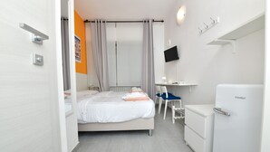 A modern hotel room with a bed, a desk, a chair, a TV, and a minibar. - Double room with private bathroom (San Lazzaro di Savena)