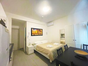 Une chambre d’hôtel comprenant un lit, une table de chevet et une table à manger avec des chaises.
