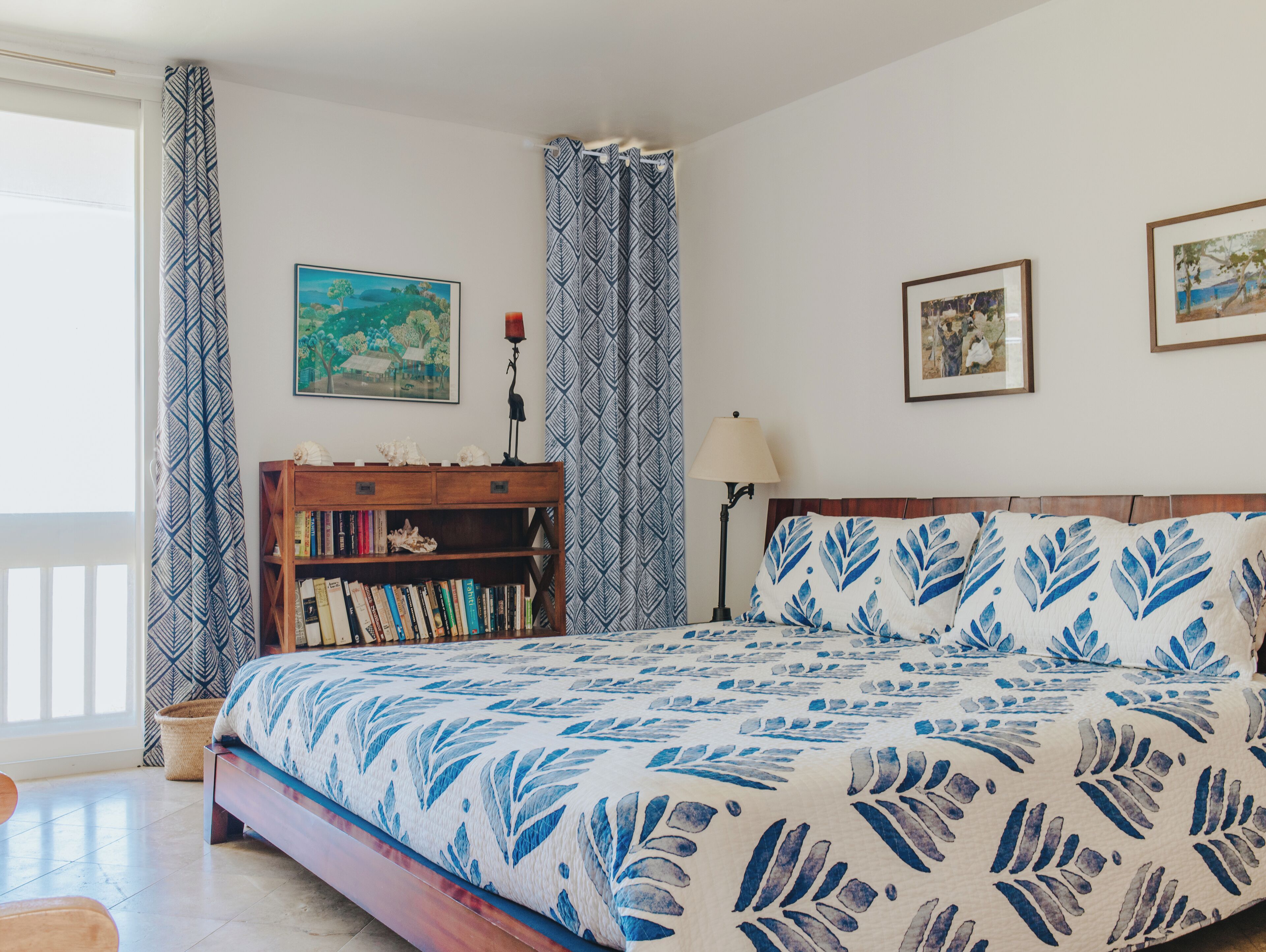 Een slaapkamer met een bed, een boekenkast en twee schilderijen aan de muur.