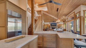 A modern kitchen with a large island, wooden cabinetry, and a ceiling fan. - Zoe's North Star at Northstar - TLUXP (Northstar)