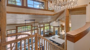 A multi-level wooden interior with a dining area, a chandelier, and large windows. - Zoe's North Star at Northstar - TLUXP (Northstar)