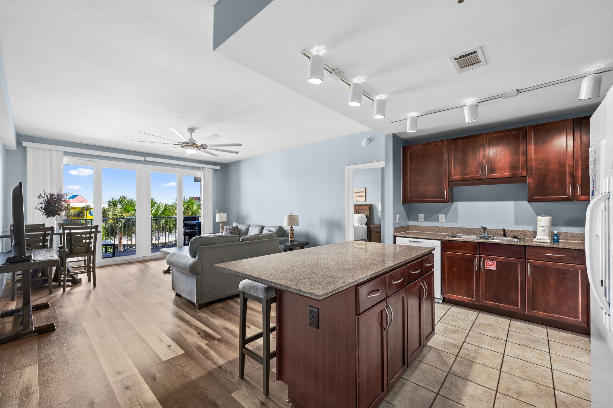 A modern kitchen with dark wood cabinets, a granite countertop, and a dining area with a table and chairs.