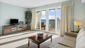 A living room with a TV, a table, a sofa, and a balcony with curtains. - Laketown Wharf condo w/ free waterpark & pools (Panama City Beach)