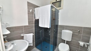 A modern bathroom with a glass-enclosed shower, a white sink, and a toilet.