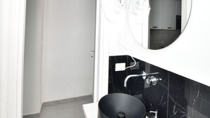 Un baño moderno con un lavamanos tipo cuenco negro, una encimera blanca y un espejo sobre el lavamanos.
