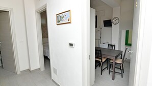 Un interior moderno con una zona de comedor que presenta una mesa y sillas de madera oscura, un reloj montado en la pared y un cuadro enmarcado.