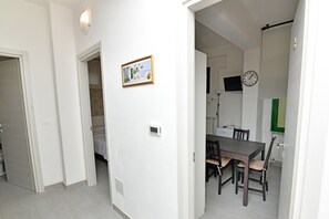 A modern interior with a dining area featuring a dark wooden table and chairs, a wall-mounted clock, and a framed picture. - Family Room with private bathroom (San Lazzaro di Savena)