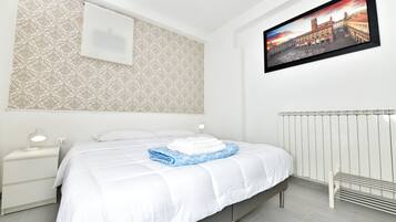Une chambre d’hôtel avec un lit, une table de chevet, un tableau accroché au mur et un radiateur.