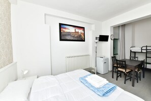 A hotel room with a bed, a desk, a chair, a radiator, a TV, and a painting on the wall. - Family Room with private bathroom (San Lazzaro di Savena)