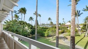 A balcony with a view of a well-maintained garden, including palm trees and neatly trimmed hedges. - Plantation Hale Suites H15, Top Floor, AC, Walk to Beach (Kapaa)