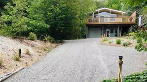 A two-story house with a gravel driveway leading to a garage.