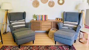 A living room with two armchairs, a wooden sideboard, and a patterned rug.