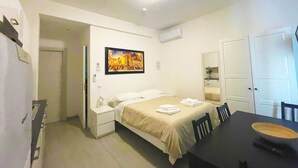 Una habitación de hotel con cama, mesita de noche y una mesa de comedor con sillas.