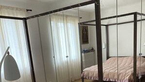 Una habitación con cama con dosel, suelo de madera, un espejo grande y un radiador.