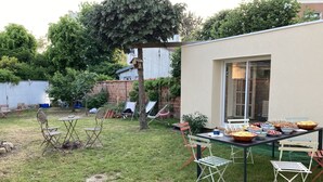 Patio con una mesa lista para una comida al aire libre, rodeada de sillas.