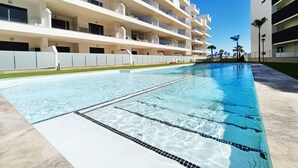 A modern hotel with a swimming pool, multiple balconies, and a clear blue sky. - Penthouse Apartment with Sea and Pool Views (San Javier)