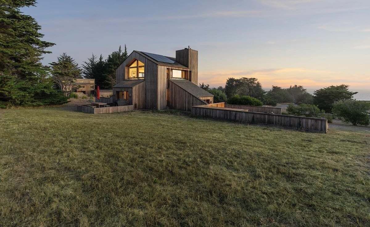 A modern house with a sloped roof, large windows, and a wooden exterior.