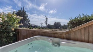 A hot tub in a backyard with a wooden fence and trees in the background.