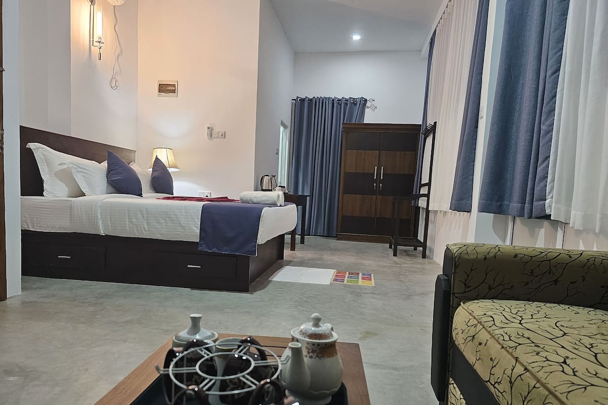 A bedroom with a bed, bedside table, lamp, wardrobe, and a coffee table with teapots.