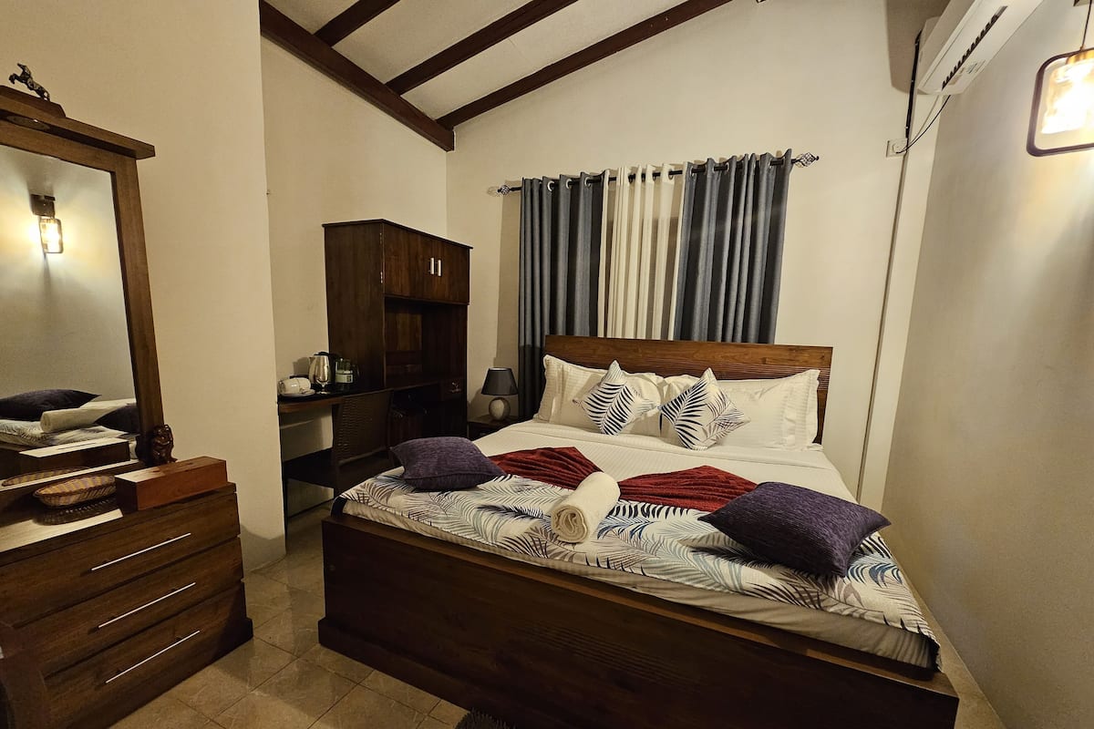 A bedroom with a wooden bed, a dresser, a desk, and a mirror.