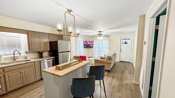 A modern kitchen with a central island, bar stools, and a dining area with a sofa.