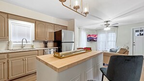 A modern kitchen with a central island, built-in appliances, and a ceiling fan.