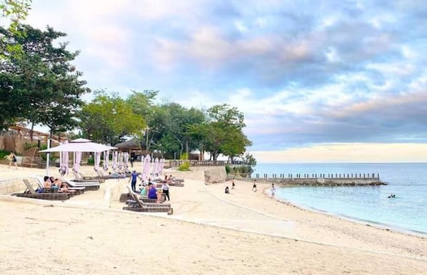 Privat strand, vit sandstrand och parasoller