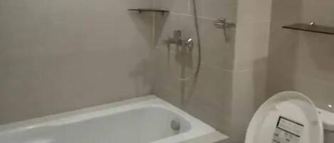 A bathroom with a bathtub, toilet, and shower.