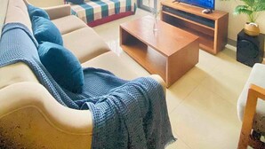 Een moderne woonkamer met een bank, een salontafel, een televisie en een plant.
