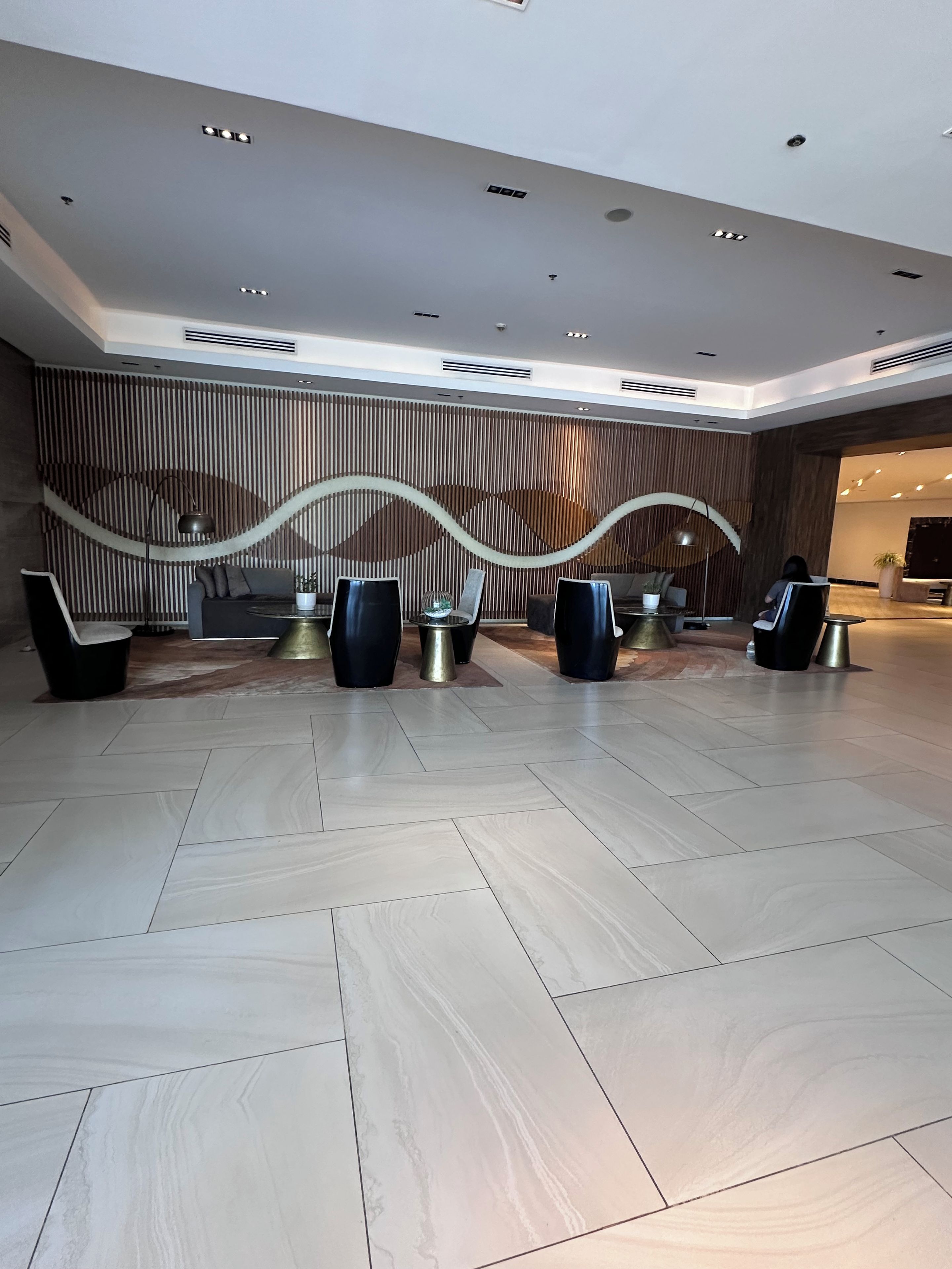A spacious lobby with a modern design, featuring a reception desk, seating area, and a decorative wall.