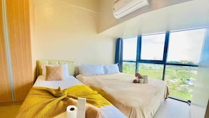 Een hotelkamer met twee bedden, een groot raam en een airconditioning.
