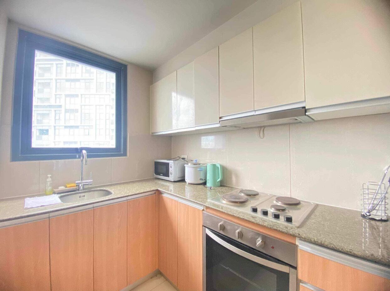 A compact kitchen with a sink, microwave, toaster, kettle, and stove.