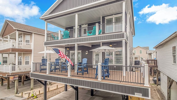 A two-story house with a balcony, outdoor furniture, and an American flag. - Beach Haven 1147, Short walk to the Beach Discounted weeks Book Now! (Myrtle Beach)