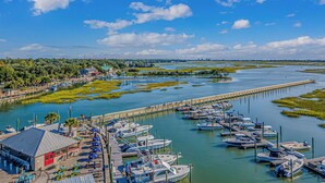 A marina with boats docked, a pier extending into the water, and a building with a red door. - Beach Haven 1147, Short walk to the Beach Discounted weeks Book Now! (Myrtle Beach)