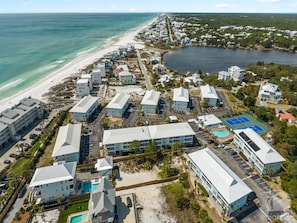 Vista aérea de un complejo turístico costero con varios edificios, una playa y una gran masa de agua.