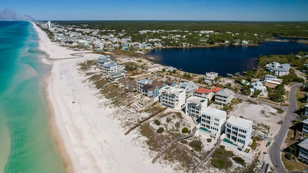 An aerial view of a coastal area with a beach, a marina, and residential buildings.