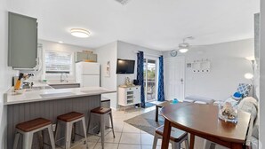 A compact kitchen with a central island, bar stools, and a dining table.